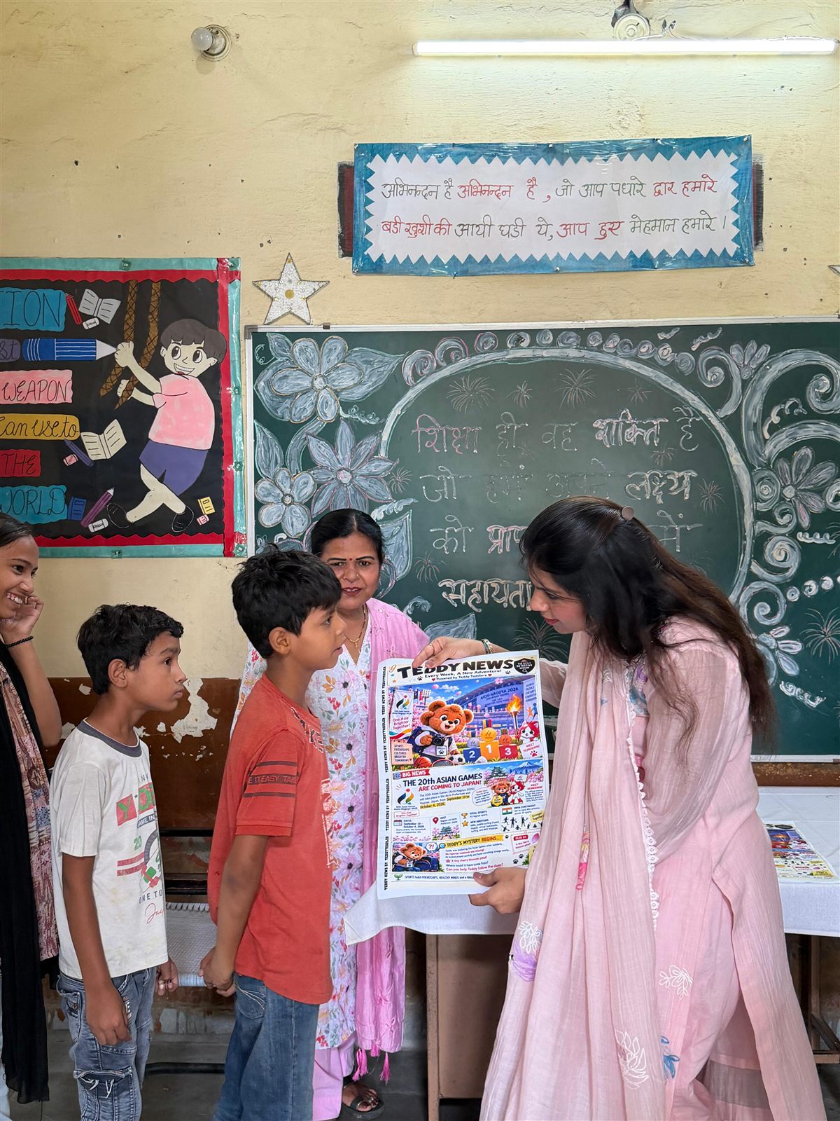 Children and a teacher gathered around a Teddy News issue in their classroom
